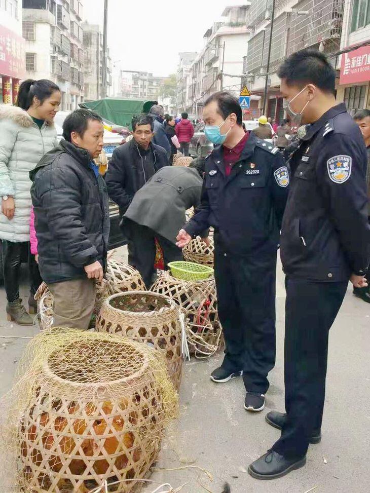 市場で野生動物の違法販売を取り締まる警察官(右の2人)=1月、中国江西省(新華社=共同)