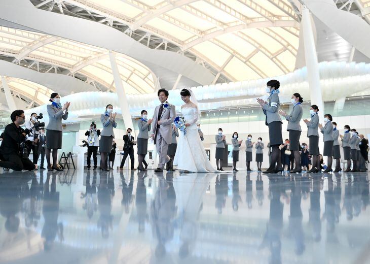 コロナ禍で減便が続く国際線の旅客機で結婚式のサービスが始まった。新郎新婦は国際線出発ロビーで参列者やスタッフに迎えられた =羽田空港(宮崎瑞穂撮影)