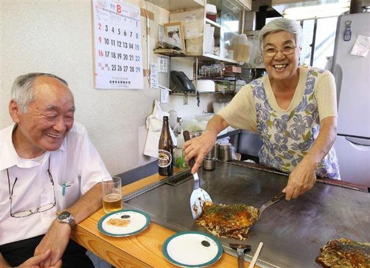常連客の前でお好み焼きを焼く梶山敏子さん=6日午前、広島市南区の「カジサン」(恵守乾撮影)
