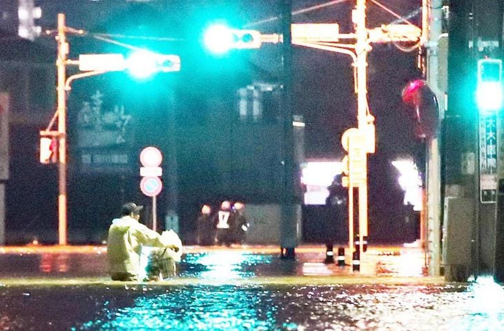 千葉県茂原市内で冠水した道路。自転車を押して歩く男性の腰あたりまで水位があった=25日夜、千葉県茂原市(佐藤徳昭撮影)
