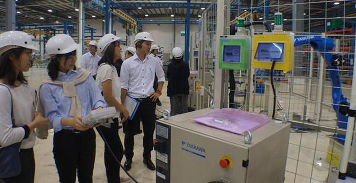 安川電機が江蘇省常州市で本格生産を開始した産業用ロボット工場で、青く塗装されたロボットアーム(右)の操作を体験する中央大学の学生(河崎真澄撮影)
